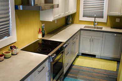 Example of an eclectic l-shaped eat-in kitchen design in Seattle with an integrated sink, flat-panel cabinets, white cabinets, concrete countertops, cement tile backsplash and stainless steel appliances