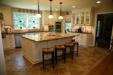 Example of a large classic u-shaped travertine floor and beige floor eat-in kitchen design in New York with an island, a double-bowl sink, recessed-panel cabinets, white cabinets, granite countertops, beige backsplash, ceramic backsplash and stainless steel appliances