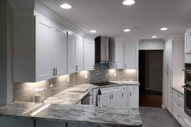Example of a mid-sized minimalist l-shaped laminate floor and gray floor kitchen design in Raleigh with a drop-in sink, white cabinets, marble countertops, white backsplash, stainless steel appliances and multicolored countertops
