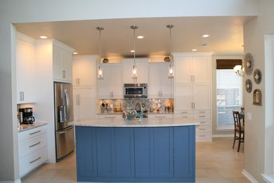 Example of a mid-sized transitional u-shaped porcelain tile eat-in kitchen design in Dallas with an undermount sink, flat-panel cabinets, white cabinets, quartzite countertops, blue backsplash, glass tile backsplash, stainless steel appliances and an island