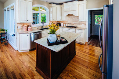 Enclosed kitchen - mid-sized transitional l-shaped medium tone wood floor enclosed kitchen idea in Philadelphia with an undermount sink, raised-panel cabinets, white cabinets, granite countertops, beige backsplash, ceramic backsplash, stainless steel appliances and an island