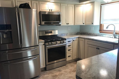 Medium sized traditional u-shaped kitchen/diner in Other with a double-bowl sink, recessed-panel cabinets, white cabinets, laminate countertops, stainless steel appliances and a breakfast bar.
