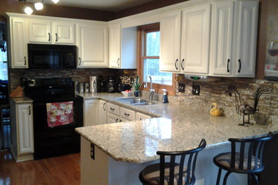 Cette image montre une cuisine américaine traditionnelle en U avec un évier encastré, des portes de placard blanches et un plan de travail en granite.
