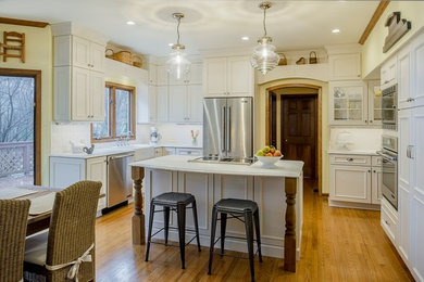 Inspiration for a large cottage u-shaped medium tone wood floor kitchen remodel in Chicago with a farmhouse sink, flat-panel cabinets, white cabinets, marble countertops, white backsplash, subway tile backsplash, stainless steel appliances and an island
