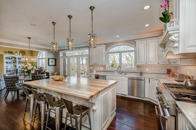 Large transitional l-shaped dark wood floor and brown floor eat-in kitchen photo in Other with raised-panel cabinets, white cabinets, white backsplash, subway tile backsplash, an island, an undermount sink, stainless steel appliances and quartz countertops