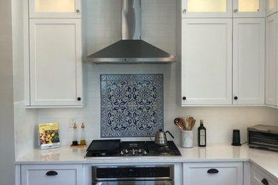 Foto de cocina clásica renovada de tamaño medio con armarios estilo shaker, puertas de armario blancas, encimera de cuarcita, suelo de madera en tonos medios y una isla
