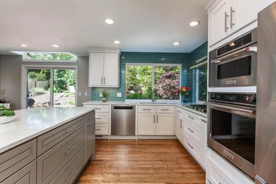 Inspiration for a medium tone wood floor and brown floor kitchen remodel in Seattle with an undermount sink, shaker cabinets, white cabinets, quartz countertops, glass tile backsplash, stainless steel appliances, an island and white countertops