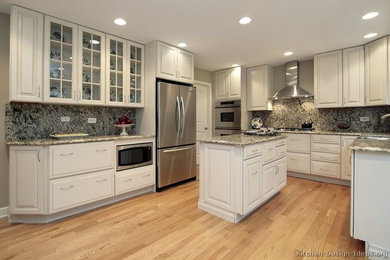 Inspiration for an u-shaped light wood floor kitchen remodel in Los Angeles with a single-bowl sink, shaker cabinets, white cabinets, granite countertops, gray backsplash, stone slab backsplash, stainless steel appliances and an island