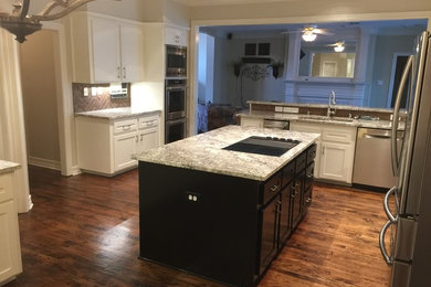 Example of a large transitional medium tone wood floor and brown floor open concept kitchen design in Dallas with an undermount sink, shaker cabinets, white cabinets, granite countertops, brown backsplash, stainless steel appliances and an island