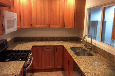 Example of a small classic galley porcelain tile enclosed kitchen design with a double-bowl sink, recessed-panel cabinets, light wood cabinets, granite countertops, stainless steel appliances and no island