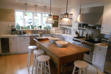 ミルウォーキーにある高級な広いインダストリアルスタイルのおしゃれなキッチン (一体型シンク、シェーカースタイル扉のキャビネット、白いキャビネット、木材カウンター、メタリックのキッチンパネル、メタルタイルのキッチンパネル、シルバーの調理設備、淡色無垢フローリング、ベージュの床) の写真