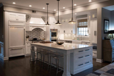 Inspiration for a mid-sized craftsman l-shaped dark wood floor and brown floor eat-in kitchen remodel in New York with a farmhouse sink, recessed-panel cabinets, white cabinets, marble countertops, multicolored backsplash, cement tile backsplash, paneled appliances, an island and white countertops