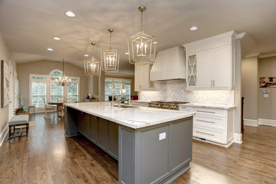 Example of a large transitional l-shaped medium tone wood floor open concept kitchen design in Atlanta with an undermount sink, beaded inset cabinets, white cabinets, quartz countertops, white backsplash, marble backsplash, stainless steel appliances, an island and white countertops