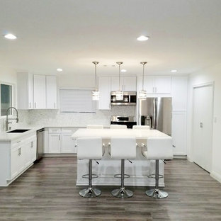 Inspiration for a large modern l-shaped eat-in kitchen in Seattle with shaker cabinets, white cabinets, quartzite benchtops, with island, turquoise benchtop, stainless steel appliances, an integrated sink, laminate floors and grey floor.