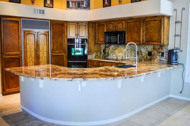 Example of a large classic l-shaped ceramic tile kitchen pantry design in Phoenix with a drop-in sink, raised-panel cabinets, dark wood cabinets, marble countertops, multicolored backsplash, stone tile backsplash, black appliances and an island