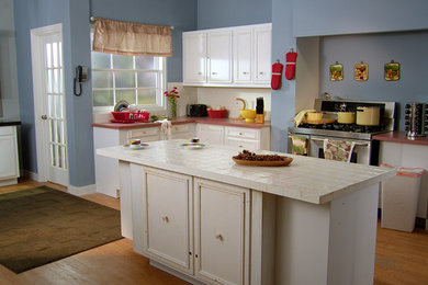 Large elegant l-shaped medium tone wood floor eat-in kitchen photo in Seattle with flat-panel cabinets, white cabinets, tile countertops, stainless steel appliances and an island