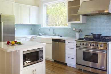 Eat-in kitchen - mid-sized transitional l-shaped medium tone wood floor and brown floor eat-in kitchen idea in San Francisco with a farmhouse sink, shaker cabinets, white cabinets, blue backsplash, stainless steel appliances, a peninsula and subway tile backsplash