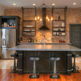 Mid-sized industrial open concept kitchen ideas - Mid-sized urban l-shaped ceramic tile and beige floor open concept kitchen photo in Orlando with brick backsplash, stainless steel appliances, an island, an undermount sink, brown cabinets, concrete countertops, red backsplash and raised-panel cabinets