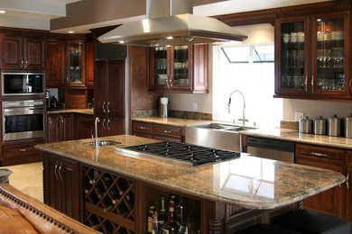 Inspiration for a large timeless l-shaped limestone floor and beige floor open concept kitchen remodel in Phoenix with an undermount sink, raised-panel cabinets, dark wood cabinets, granite countertops, paneled appliances and an island