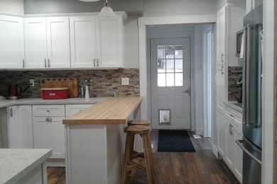 Mid-sized transitional u-shaped laminate floor and brown floor eat-in kitchen photo in Other with an undermount sink, shaker cabinets, white cabinets, quartz countertops, multicolored backsplash, glass tile backsplash, stainless steel appliances, a peninsula and multicolored countertops