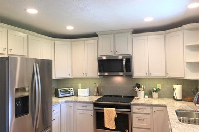 Example of a mid-sized classic u-shaped enclosed kitchen design in Indianapolis with a double-bowl sink, shaker cabinets, white cabinets, granite countertops, green backsplash, subway tile backsplash and stainless steel appliances