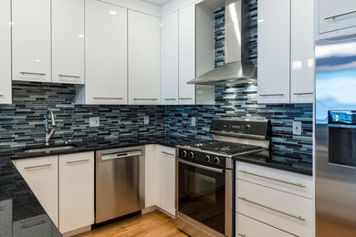 ボストンにある高級な小さなモダンスタイルのおしゃれなキッチン (アンダーカウンターシンク、フラットパネル扉のキャビネット、白いキャビネット、珪岩カウンター、青いキッチンパネル、ガラス板のキッチンパネル、シルバーの調理設備、淡色無垢フローリング) の写真