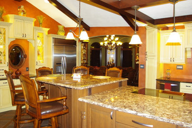 Foto de cocina clásica grande con armarios con paneles con relieve, puertas de armario beige, encimera de granito, electrodomésticos de acero inoxidable, suelo de madera oscura y una isla