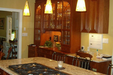 Inspiration for a large transitional l-shaped medium tone wood floor open concept kitchen remodel in Atlanta with a farmhouse sink, raised-panel cabinets, medium tone wood cabinets, granite countertops, yellow backsplash, stainless steel appliances and an island