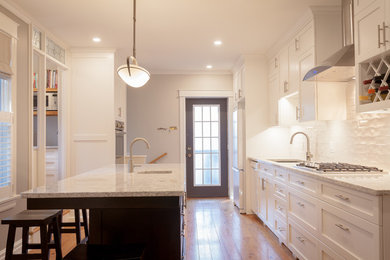 Mid-sized transitional single-wall medium tone wood floor eat-in kitchen photo in Toronto with a single-bowl sink, recessed-panel cabinets, white cabinets, white backsplash, subway tile backsplash, stainless steel appliances, an island and marble countertops