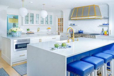Beach style light wood floor and beige floor eat-in kitchen photo in New York with a farmhouse sink, white cabinets, white backsplash, stainless steel appliances, two islands, white countertops, shaker cabinets and mosaic tile backsplash