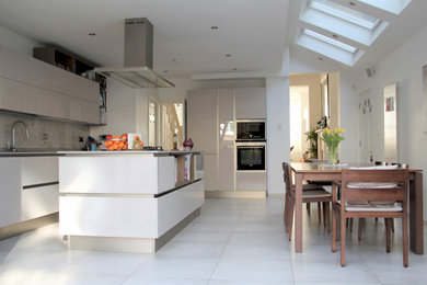 Photo of a large contemporary kitchen in London with a double-bowl sink, glass-front cabinets, multi-coloured splashback, ceramic splashback, integrated appliances, ceramic flooring, an island, grey floors and multicoloured worktops.