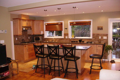 Example of a classic l-shaped light wood floor eat-in kitchen design in Vancouver with an undermount sink, recessed-panel cabinets, light wood cabinets, onyx countertops, beige backsplash, stone tile backsplash and an island