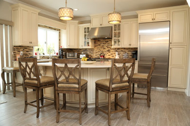 Example of a mid-sized classic l-shaped beige floor and porcelain tile eat-in kitchen design in New York with raised-panel cabinets, beige cabinets, beige backsplash, matchstick tile backsplash, stainless steel appliances, an island, a double-bowl sink and quartz countertops