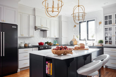 Eat-in kitchen - mid-sized transitional l-shaped medium tone wood floor and brown floor eat-in kitchen idea in St Louis with a farmhouse sink, shaker cabinets, gray cabinets, soapstone countertops, white backsplash, mosaic tile backsplash, black appliances, an island and black countertops