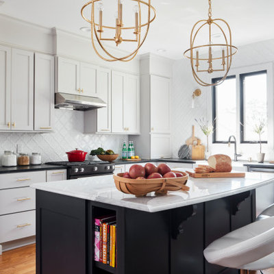 Eat-in kitchen - mid-sized transitional l-shaped medium tone wood floor and brown floor eat-in kitchen idea in St Louis with a farmhouse sink, shaker cabinets, gray cabinets, soapstone countertops, white backsplash, mosaic tile backsplash, black appliances, an island and black countertops
