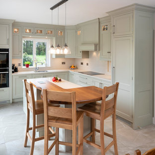 Design ideas for a mid-sized country l-shaped eat-in kitchen in Cork with a double-bowl sink, flat-panel cabinets, green cabinets, quartzite benchtops, beige splashback, stainless steel appliances, porcelain floors, with island, beige floor and beige benchtop.
