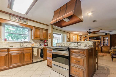 Inspiration for a mid-sized timeless l-shaped ceramic tile eat-in kitchen remodel in Jacksonville with raised-panel cabinets, granite countertops, stainless steel appliances, an island, medium tone wood cabinets and beige backsplash