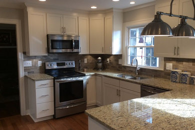 Example of a transitional u-shaped medium tone wood floor kitchen design in Other with an undermount sink, shaker cabinets, white cabinets, granite countertops, beige backsplash, subway tile backsplash, stainless steel appliances and a peninsula