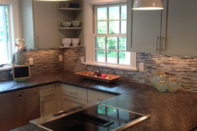 Inspiration for a mid-sized timeless u-shaped medium tone wood floor enclosed kitchen remodel in New York with a farmhouse sink, shaker cabinets, gray cabinets, granite countertops, metallic backsplash, metal backsplash, stainless steel appliances and a peninsula