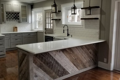 Foto de cocina comedor rural de tamaño medio con fregadero sobremueble, armarios estilo shaker, puertas de armario grises, encimera de cuarzo compacto, salpicadero blanco, salpicadero de azulejos tipo metro, suelo de madera en tonos medios, península, suelo marrón y encimeras blancas