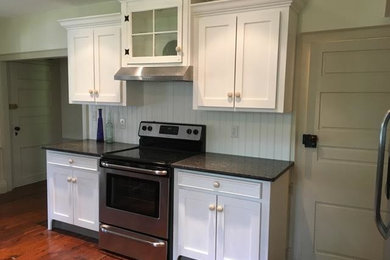 Example of a mid-sized classic l-shaped medium tone wood floor and brown floor eat-in kitchen design in Philadelphia with shaker cabinets, white cabinets, granite countertops, white backsplash, wood backsplash, stainless steel appliances and no island