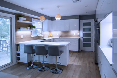 This is an example of a medium sized modern u-shaped enclosed kitchen with a submerged sink, flat-panel cabinets, white cabinets, engineered stone countertops, brown splashback, porcelain splashback, stainless steel appliances, porcelain flooring, a breakfast bar, brown floors and white worktops.