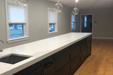 Inspiration for a transitional medium tone wood floor and beige floor eat-in kitchen remodel in Boston with shaker cabinets, black cabinets, quartzite countertops, white backsplash, quartz backsplash, stainless steel appliances, an island and white countertops