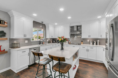 Eat-in kitchen - mid-sized transitional u-shaped laminate floor and brown floor eat-in kitchen idea in Orlando with a double-bowl sink, shaker cabinets, white cabinets, quartz countertops, gray backsplash, glass tile backsplash, stainless steel appliances, an island and white countertops
