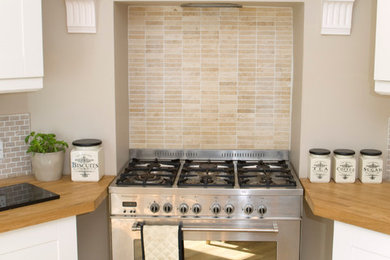 Bild på ett mellanstort funkis kök, med en rustik diskho, skåp i shakerstil, beige skåp, träbänkskiva, beige stänkskydd, stänkskydd i stenkakel, rostfria vitvaror och ljust trägolv
