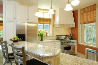 Bild på ett mellanstort lantligt kök med öppen planlösning, med luckor med upphöjd panel, vita skåp, granitbänkskiva, beige stänkskydd, stänkskydd i stenkakel, rostfria vitvaror, klinkergolv i keramik, grått golv och en halv köksö
