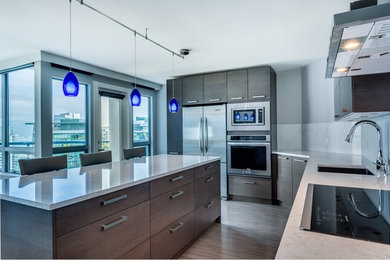 Inspiration for a large modern l-shaped light wood floor open concept kitchen remodel in Vancouver with a single-bowl sink, flat-panel cabinets, dark wood cabinets, quartzite countertops, white backsplash, stone slab backsplash, stainless steel appliances and an island