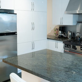 Design ideas for a mid-sized modern l-shaped open plan kitchen in Toronto with an undermount sink, flat-panel cabinets, white cabinets, granite benchtops, grey splashback, metal splashback, stainless steel appliances, ceramic floors, a peninsula, green floor and green benchtop.