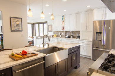 Large transitional l-shaped dark wood floor and gray floor open concept kitchen photo in New York with a farmhouse sink, shaker cabinets, white cabinets, quartz countertops, gray backsplash, porcelain backsplash, stainless steel appliances, an island and white countertops