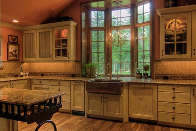 Inspiration for a mid-sized rustic l-shaped medium tone wood floor enclosed kitchen remodel in Other with a farmhouse sink, distressed cabinets, granite countertops, beige backsplash, paneled appliances, a peninsula, recessed-panel cabinets and stone tile backsplash